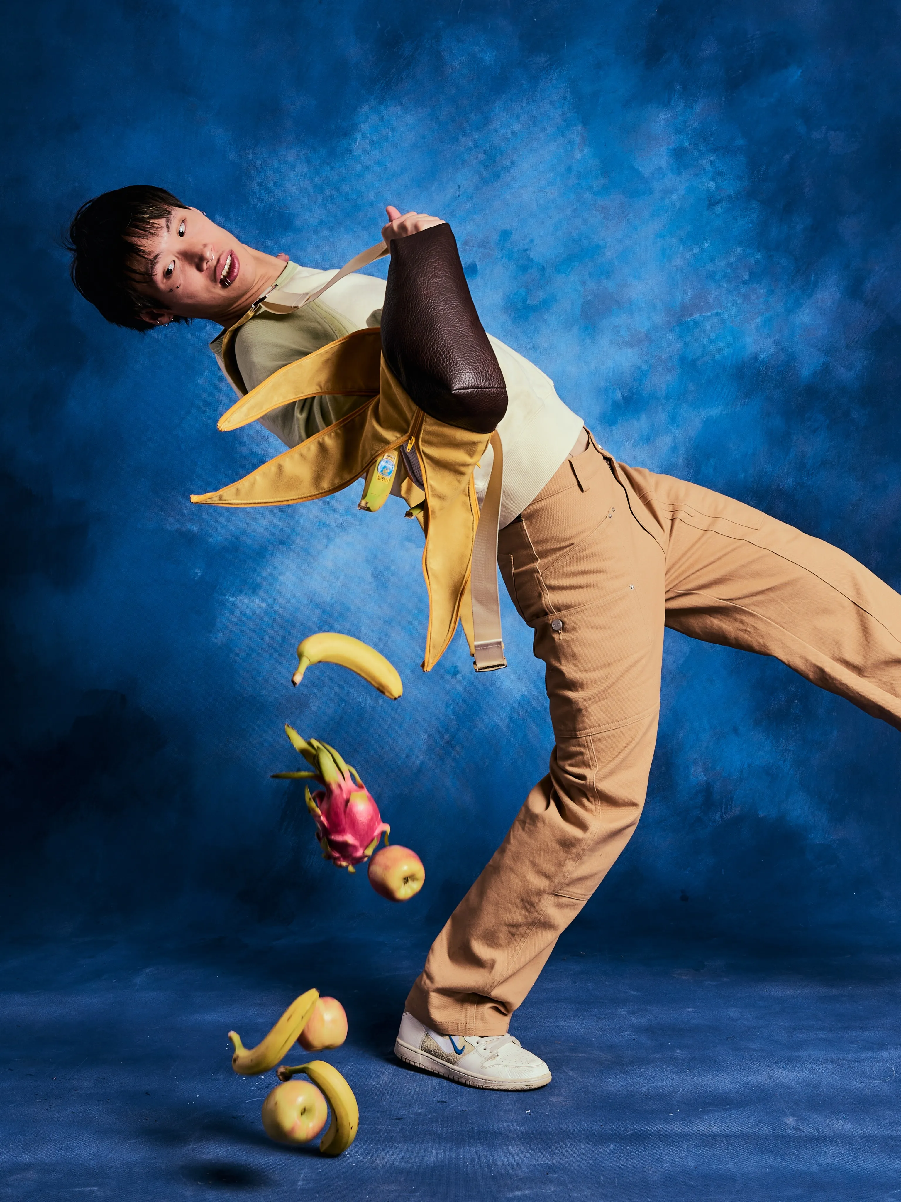 A model mid-motion, fruit falling from the bag